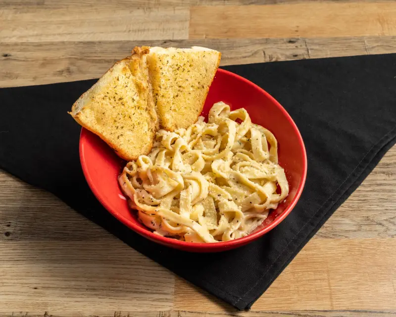Durkin&rsquo;s Fettuccine Alfredo with garlic bread in a red bowl