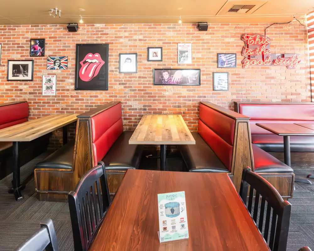Red booths and brick wall with framed rock posters inside Durkin&rsquo;s Pizza in McKinney, TX