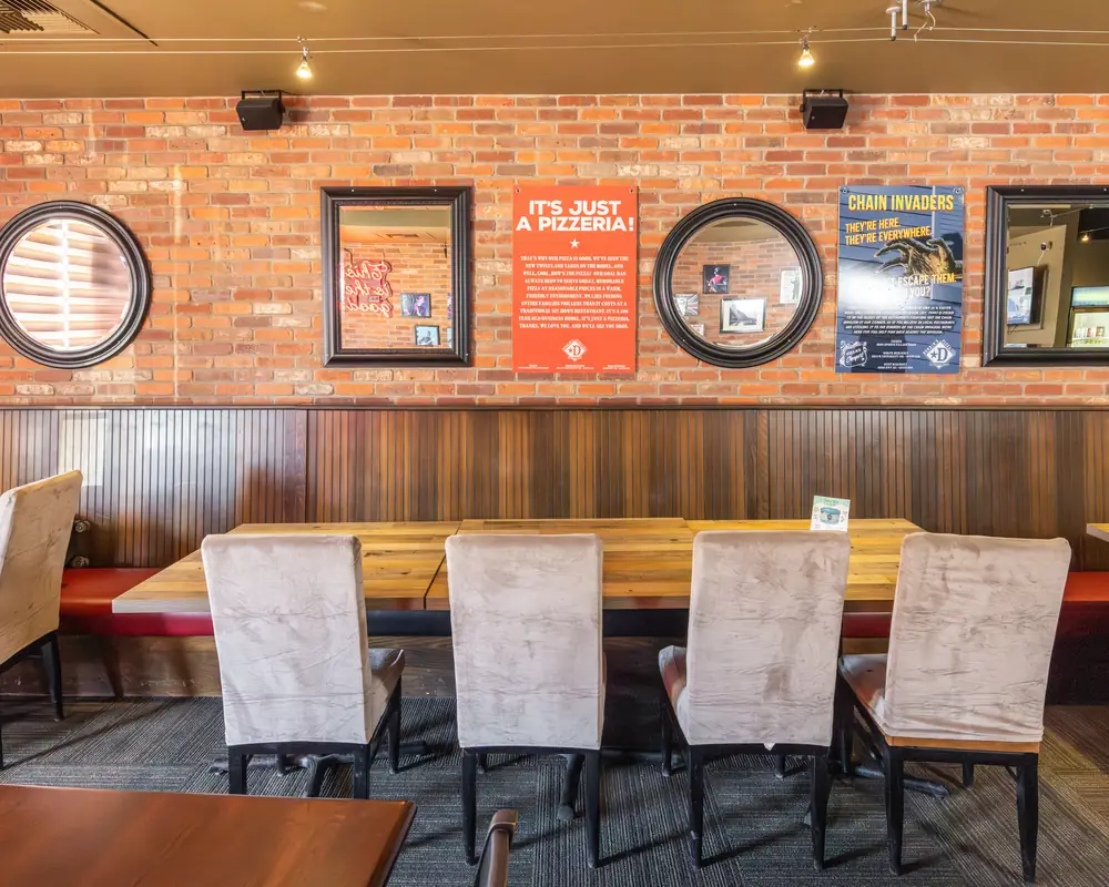 Long communal tables and brick wall at Durkin&rsquo;s Pizza in McKinney, TX